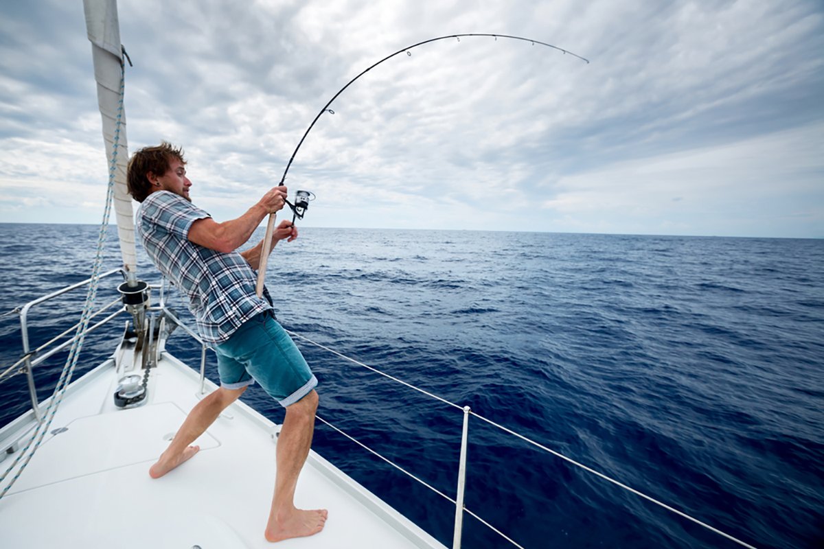 Young,Man,Fishing,In,Open,Sea,From,Sail,Boat